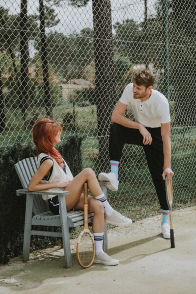 A man talking to a woman at a tennis court