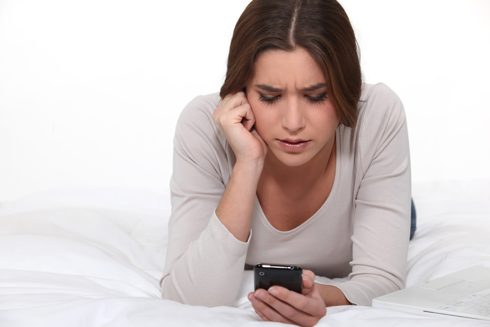 A woman on her bed texting 