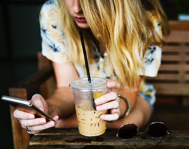 A woman texting and drinking iced coffee
