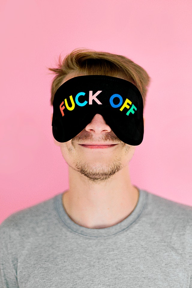 A man wearing a face mask over his eyes that read "Fuck Off" 