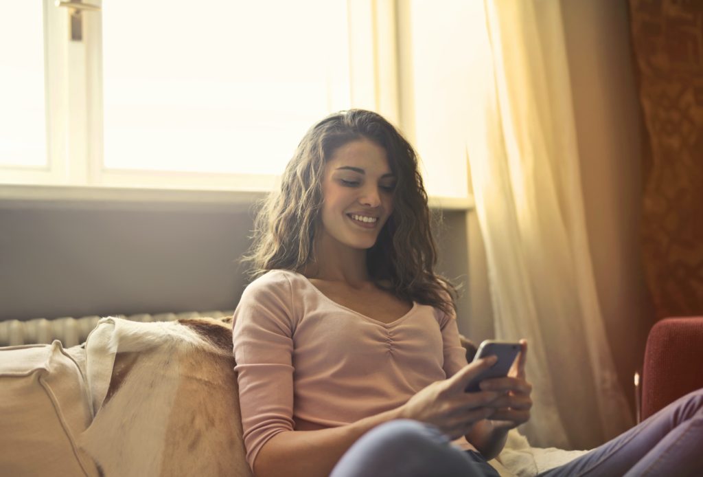 A woman on her bed texting on her phone 