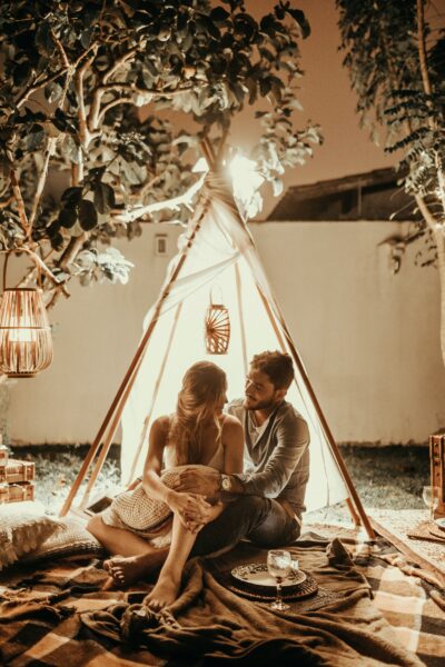 A man and woman in a romantic tent cuddling