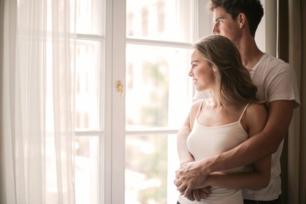 A man cuddling a woman and looking out a window