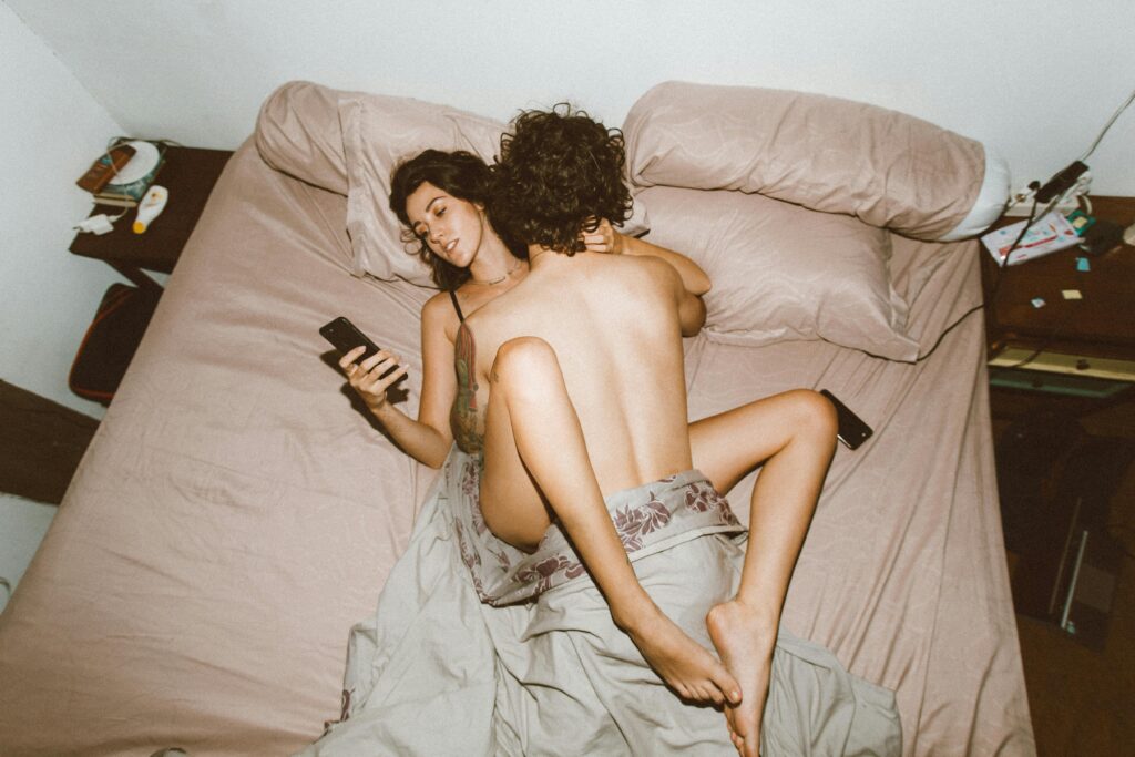 Man trying to get laid on a bed with his girlfriend but she is texting 