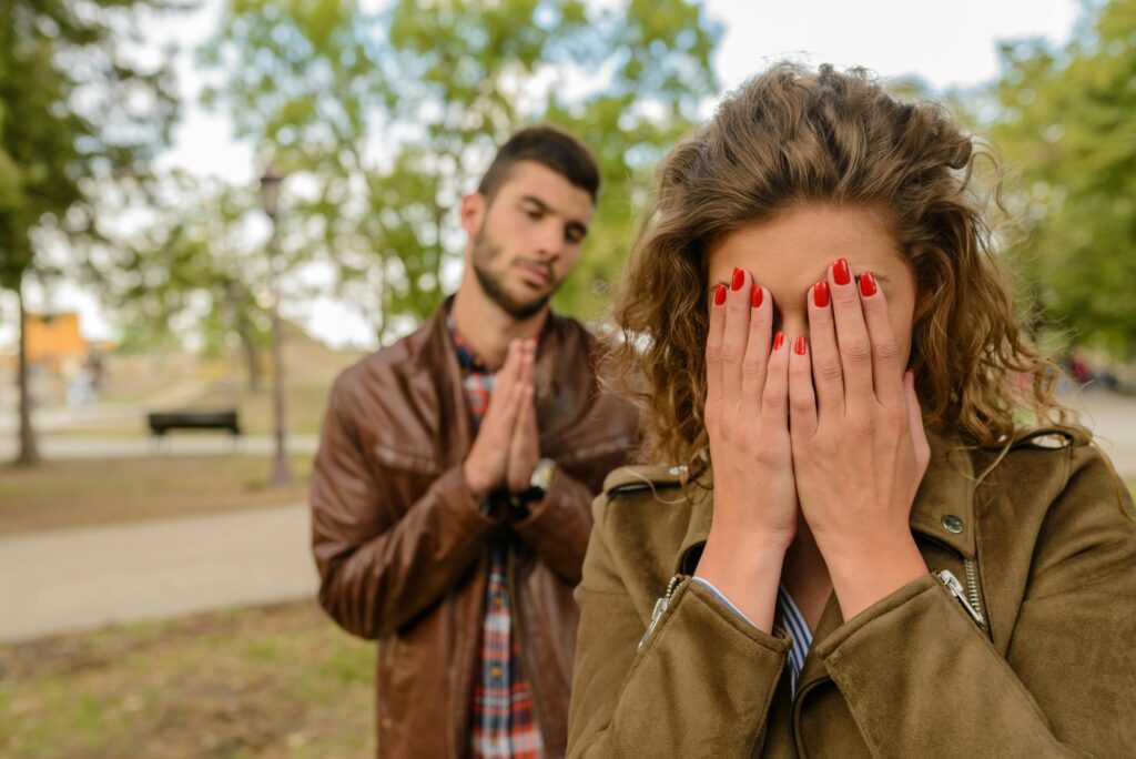 Man begging a woman who is crying on the street