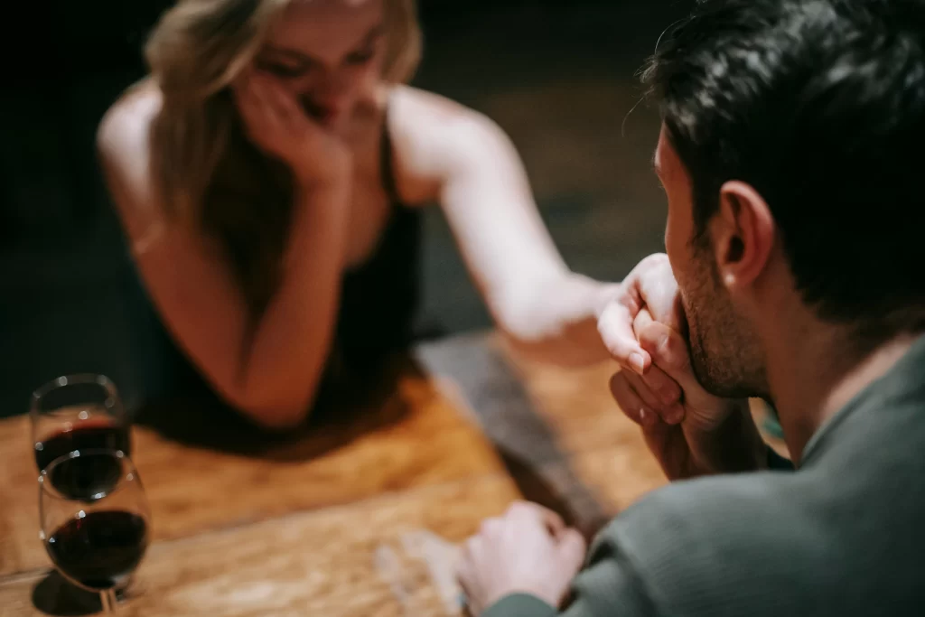 A man talking to a bored looking woman on a date in a classy restaurant