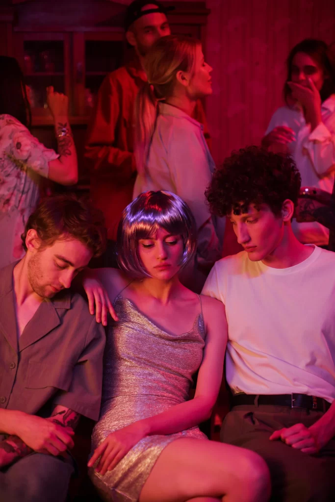 Two men and one tired woman in between them in a night club